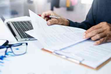 © stock.metket.com - stock.adobe.com Person mit Dokumenten und Laptop